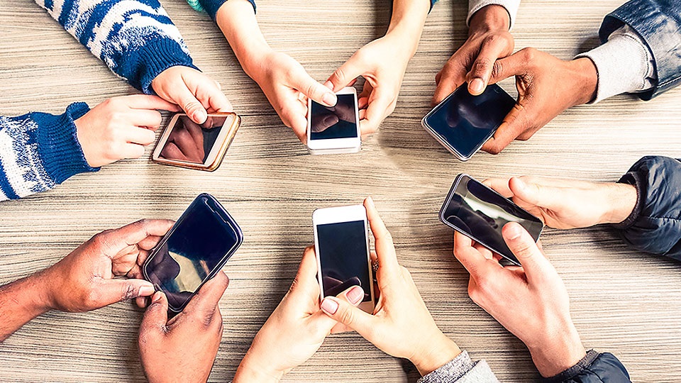 Sex personer som sitter i en ring med mobiler